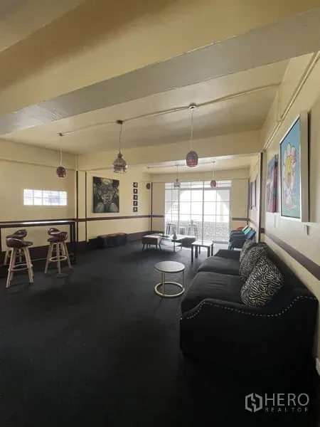 Shophouse for rent in Khlong Toei, Bangkok - Spacious upper-floor lounge in a shophouse with sofa, bar stools, pendant lights and large windows.