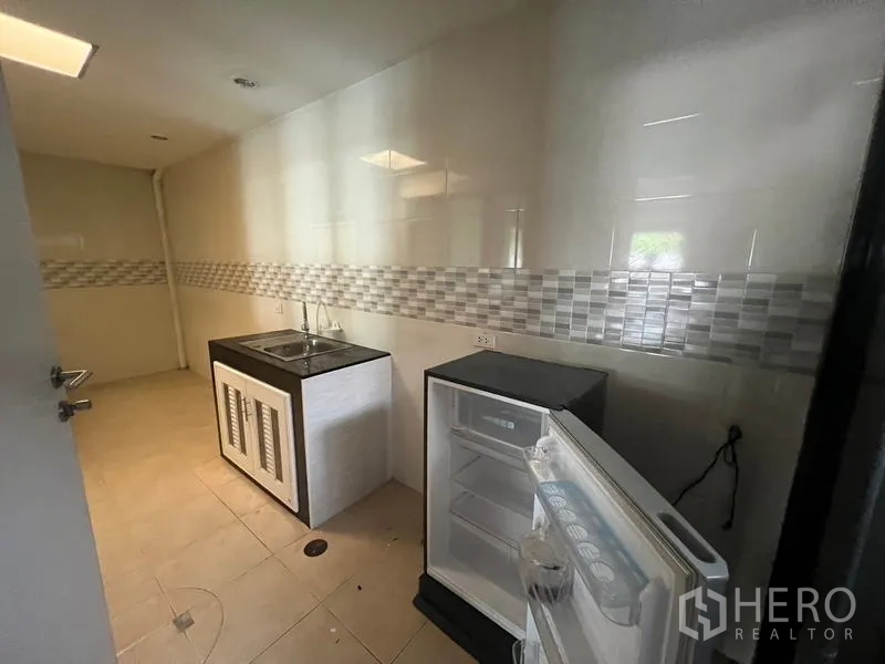 Townhouse for rent or sale in Khlong Toei, Bangkok - Secondary pantry with sink and compact refrigerator set against tiled walls.