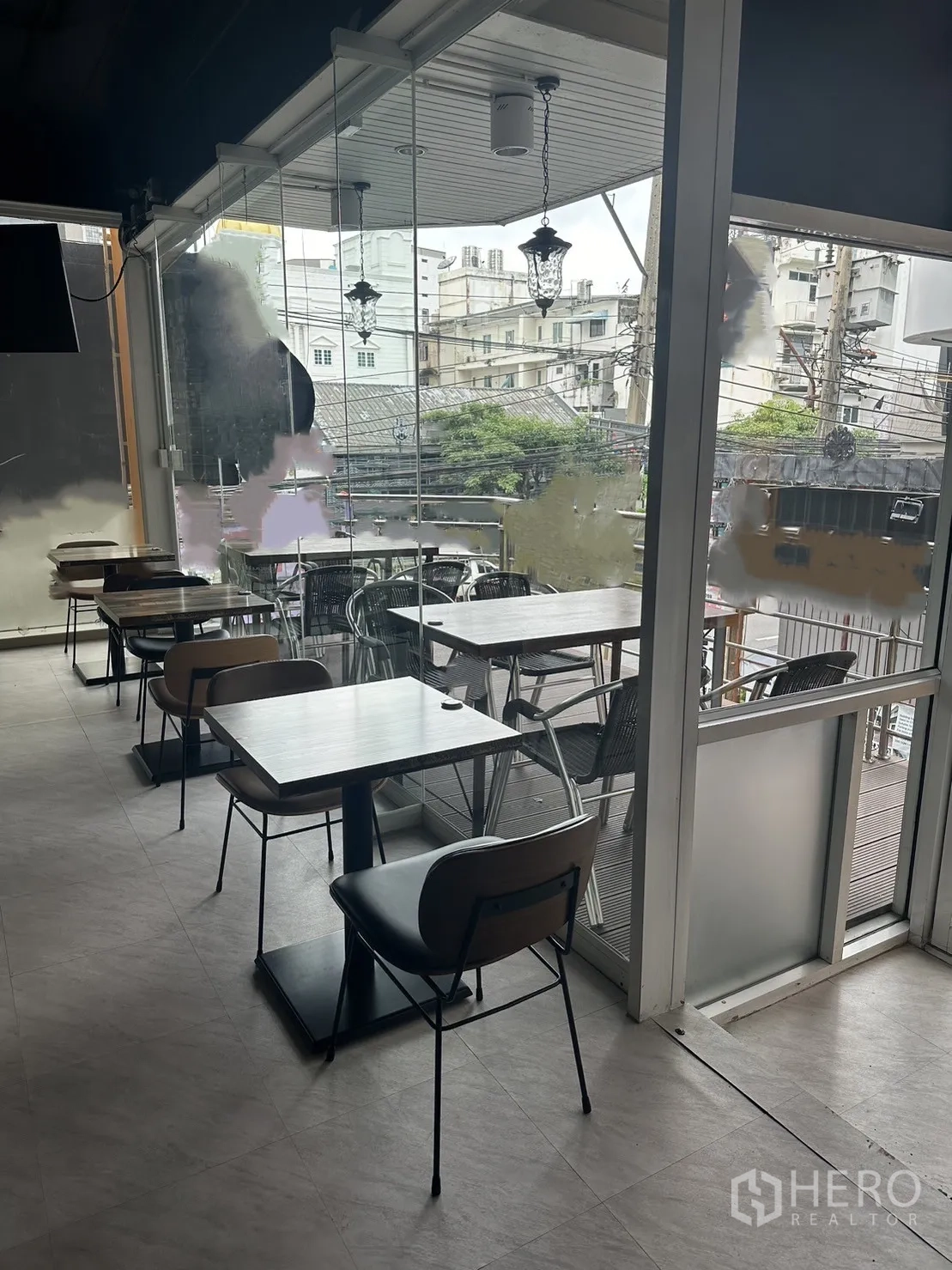 Retail Space for rent in Khlong Toei, Bangkok - Window-side two-top tables beside sliding glass leading to balcony seating.
