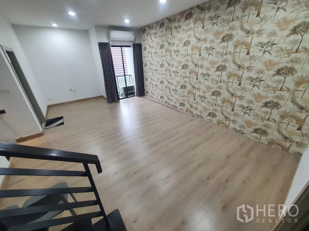 Home Office for rent in Lat Phrao, Bangkok - Upper-floor room with tropical accent wall, balcony door and wood flooring.