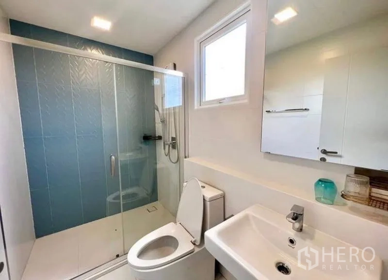 Detached House for rent - Bathroom with blue accent wall tiles, glass shower enclosure and window.