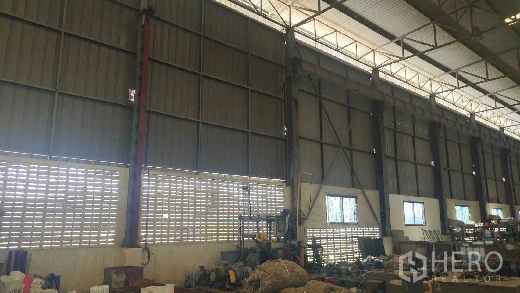 Factory for sale in Nikhom Phatthana, Rayong - Factory interior wall with ventilation blocks, machinery and tools along the side.