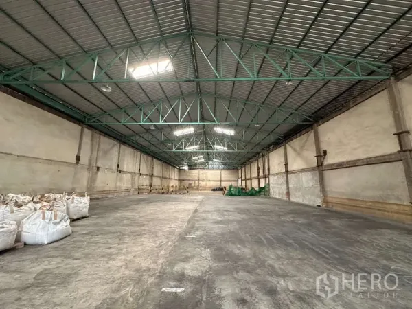 Warehouse for rent in Mueang Pathum Thani, Pathum Thani - Spacious warehouse interior featuring high steel truss roof and skylight panels.
