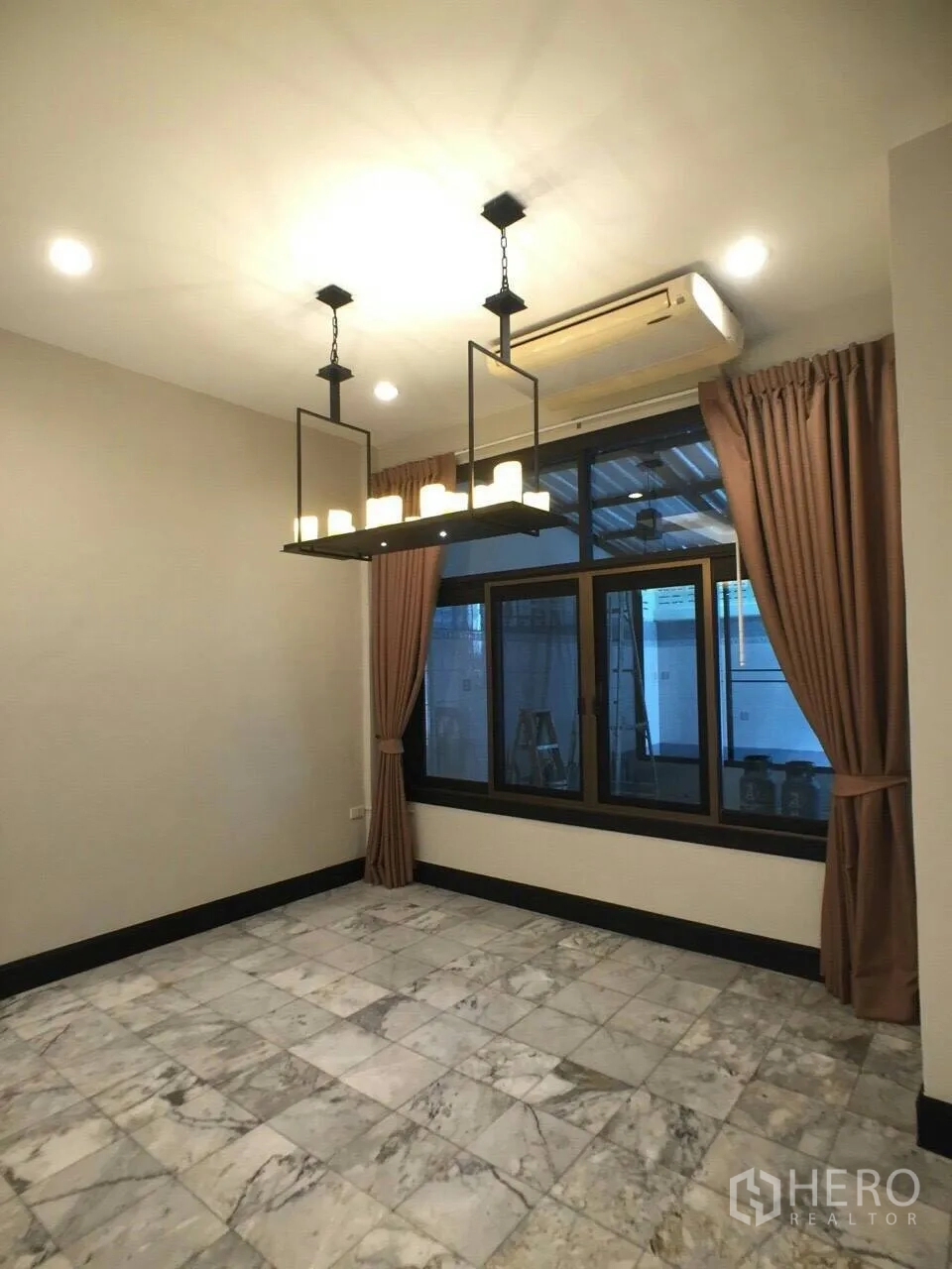 Townhouse for rent in Khlong Toei, Bangkok - Dining area with marble tile floor, large window with curtains, and rectangular pendant chandelier.