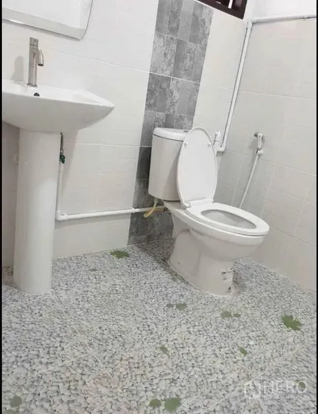 Detached House for rent in Lat Phrao, Bangkok - Simple white bathroom with pedestal sink, flush toilet and mosaic pebble‑style floor.
