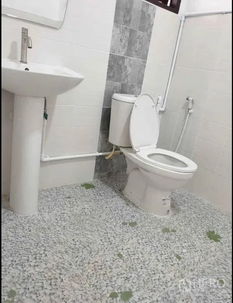 Detached House for rent in Lat Phrao, Bangkok - Simple white bathroom with pedestal sink, flush toilet and mosaic pebble‑style floor.