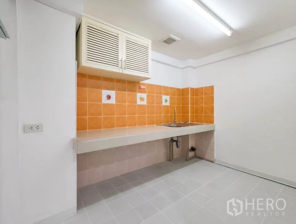Office Space for rent in Khlong Toei, Bangkok - Compact pantry with sink, wall cabinet and orange tile backsplash.