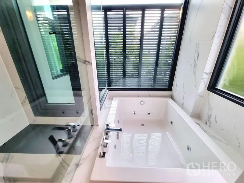 Detached House for rent - Jetted soaking tub beside corner windows with privacy louver screens in a marble bathroom.