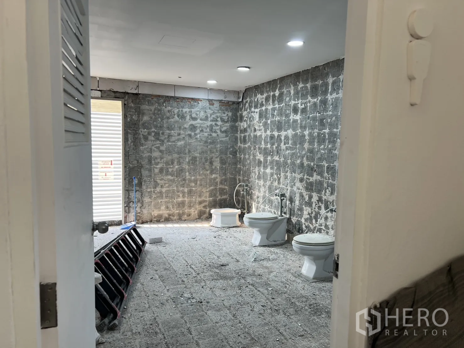 Office Space for rent in Watthana, Bangkok - View into an unfinished bathroom with multiple toilets and rough masonry walls.