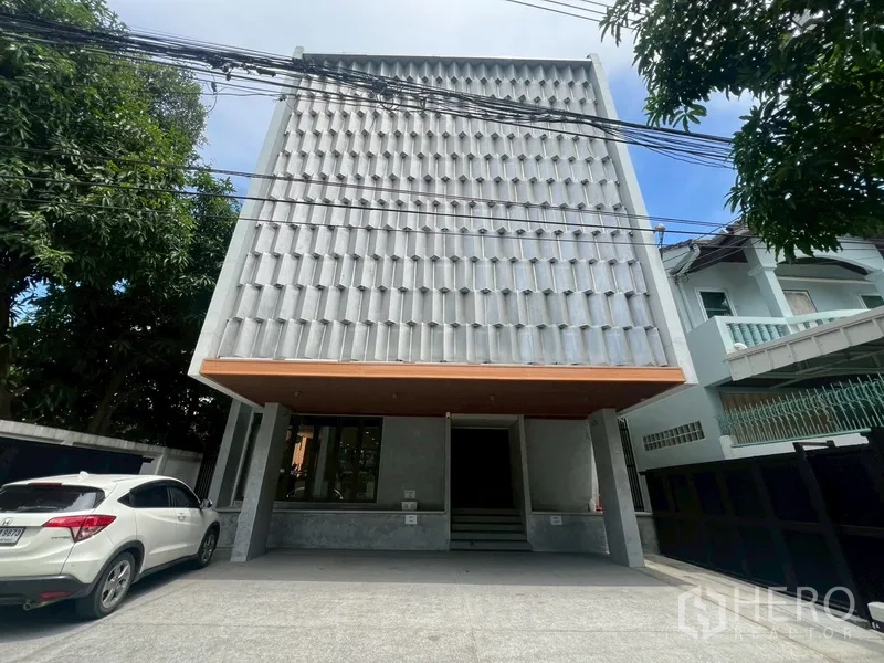Home Office for rent or sale in Phra Khanong, Bangkok - Modern 3.5‑storey home office facade with gated driveway and parking.