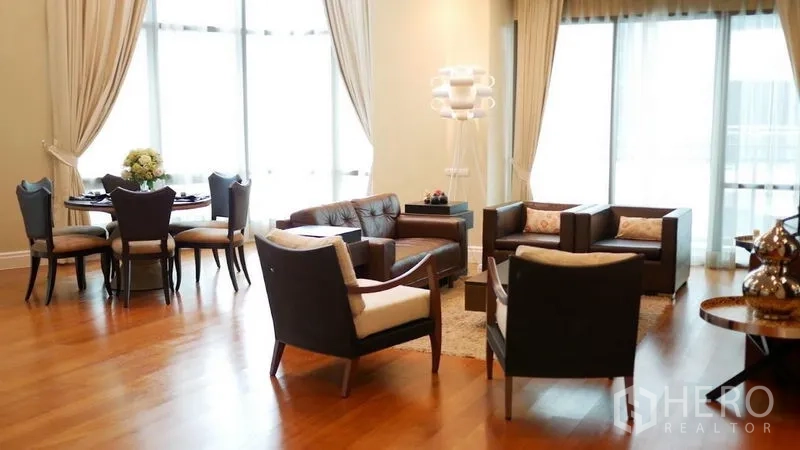 Condominium for rent in Khlong Toei, Bangkok - Another view of the open-plan living and dining area with modern armchairs and abundant natural light.