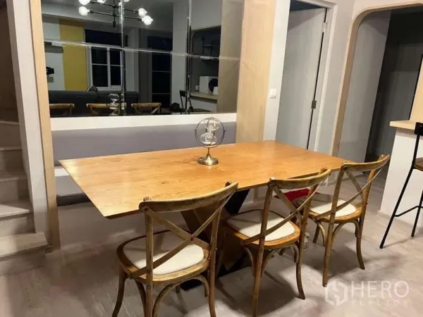 Detached House for rent in Prawet, Bangkok - Dining area with wooden table, four chairs and a mirrored feature wall.