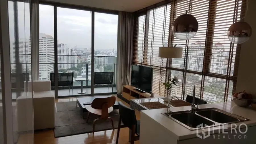 Condominium for rent in Watthana, Bangkok - Open-plan living area with floor-to-ceiling windows, balcony seating, and a wide city skyline view.