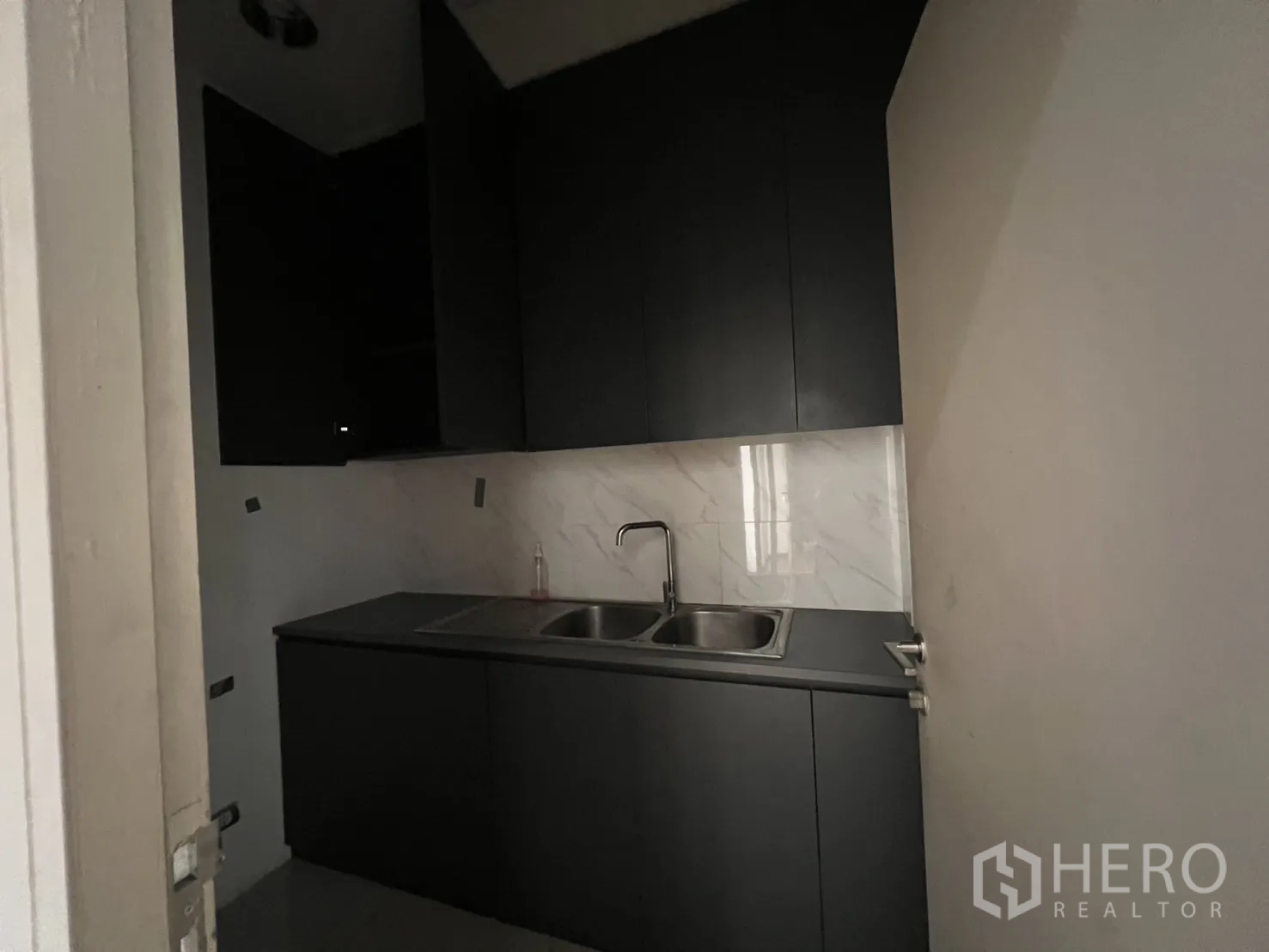 办公空间 出租在Huai Khwang, Bangkok - 紧凑茶水间，深色橱柜、不锈钢水槽与大理石背板。