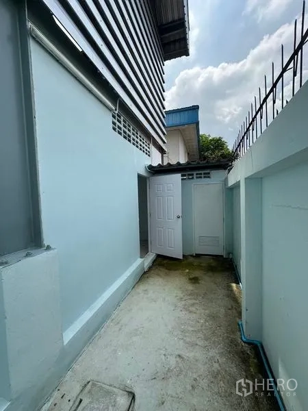 Factory for rent in Pak Kret, Nonthaburi - Narrow side passage of the building with service doors and perimeter fence.
