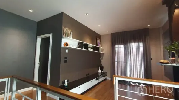 Detached House for sale in Prawet, Bangkok - Upstairs family lounge with long built-in cabinet and sliding door with sheer curtains.