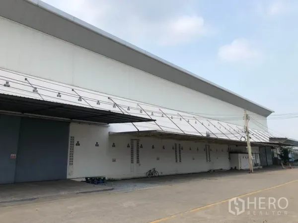 工厂 出租在Bang Bua Thong, Nonthaburi - 仓库侧立面，连续雨棚与通风窗，卡车通行宽敞。