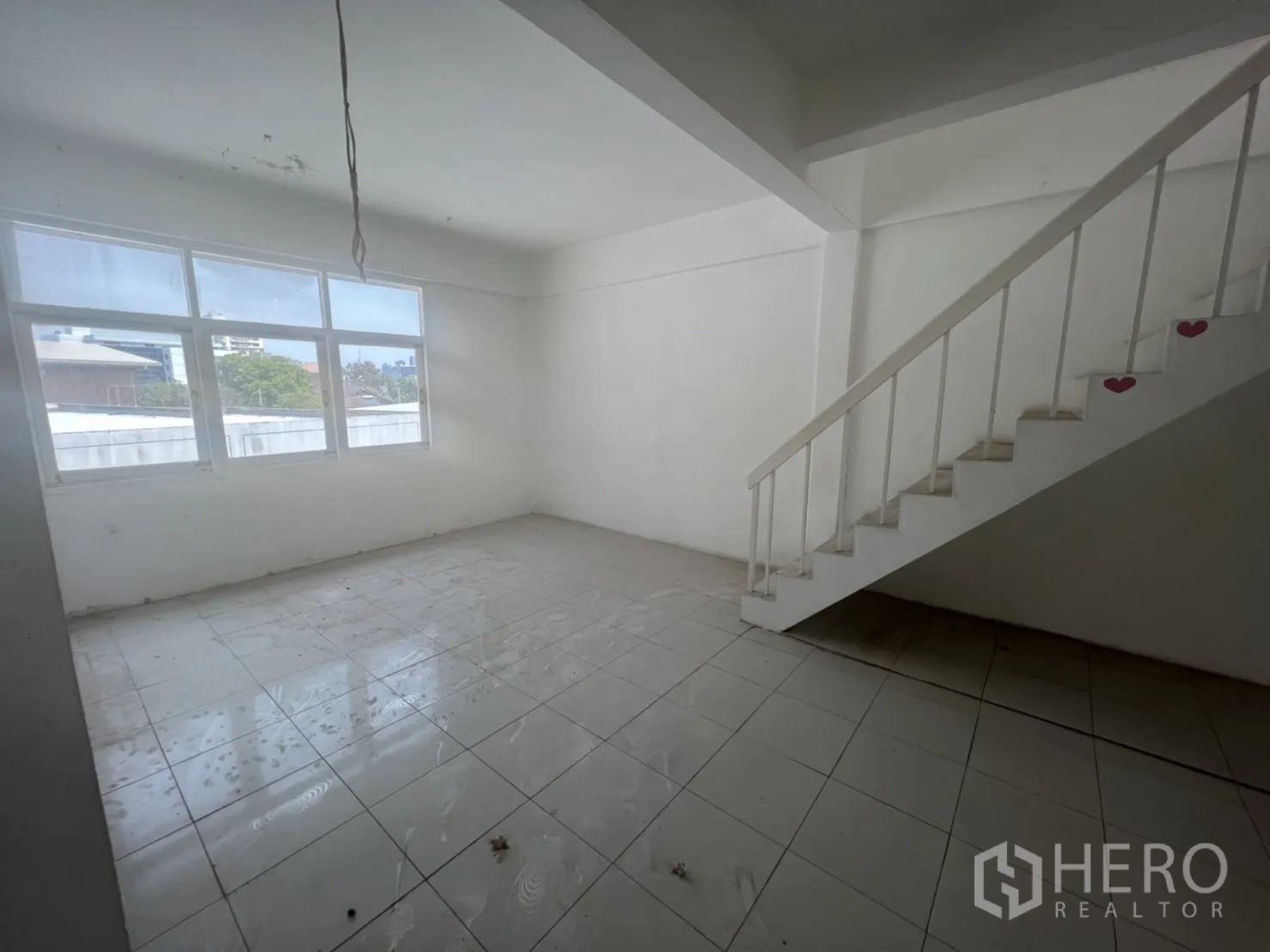 Shophouse for rent in Watthana, Bangkok - Room with a large window and straight staircase against a white wall.