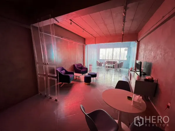 Shophouse for rent or sale in Watthana, Bangkok - Lounge area with soft seating and red ambient lighting divided by a string curtain.