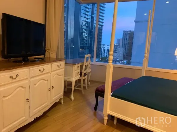 Condominium for rent in Watthana, Bangkok - Master bedroom with four-poster bed, TV console, work desk and window view of the city skyline.