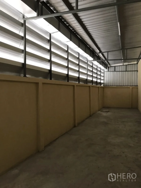 Factory for rent or sale in Mueang Samut Sakhon, Samut Sakhon - Covered side corridor with ventilation louvers and concrete walkway.