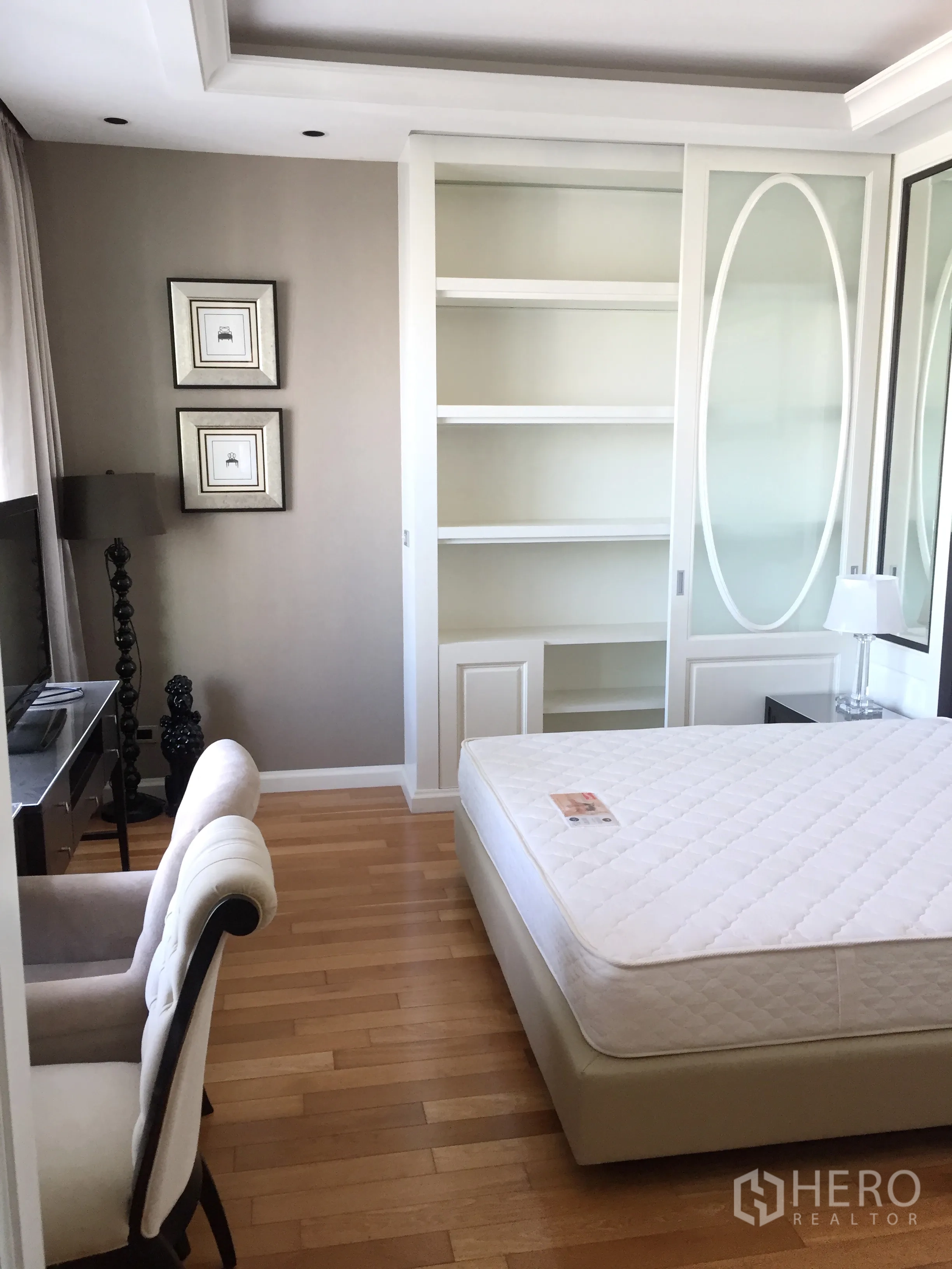 Condominium for rent in Khlong Toei, Bangkok - Master bedroom with built-in wardrobe and shelving, neutral tones, and a TV console.