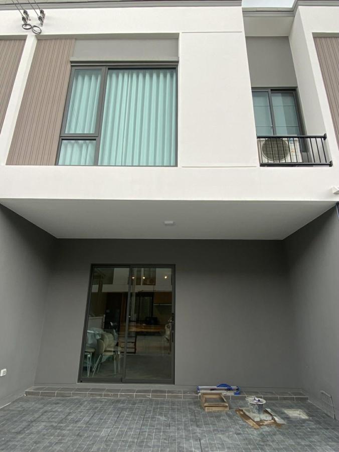 Townhouse for rent in Bang Phli, Samut Prakan - Contemporary townhouse facade with upper windows and a covered carport with sliding door.