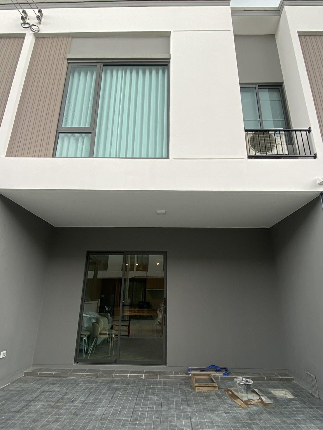 联排别墅 出租在Bang Phli, Samut Prakan - 现代联排外立面，二层大窗与带顶车棚、推拉门。