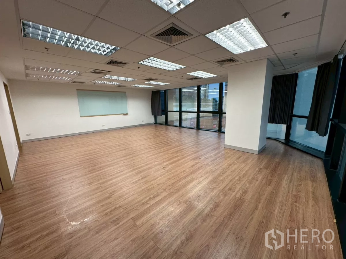 Office Space for rent in Khlong Toei, Bangkok - Large column-free office area with grid ceiling lights and wall-to-wall windows.