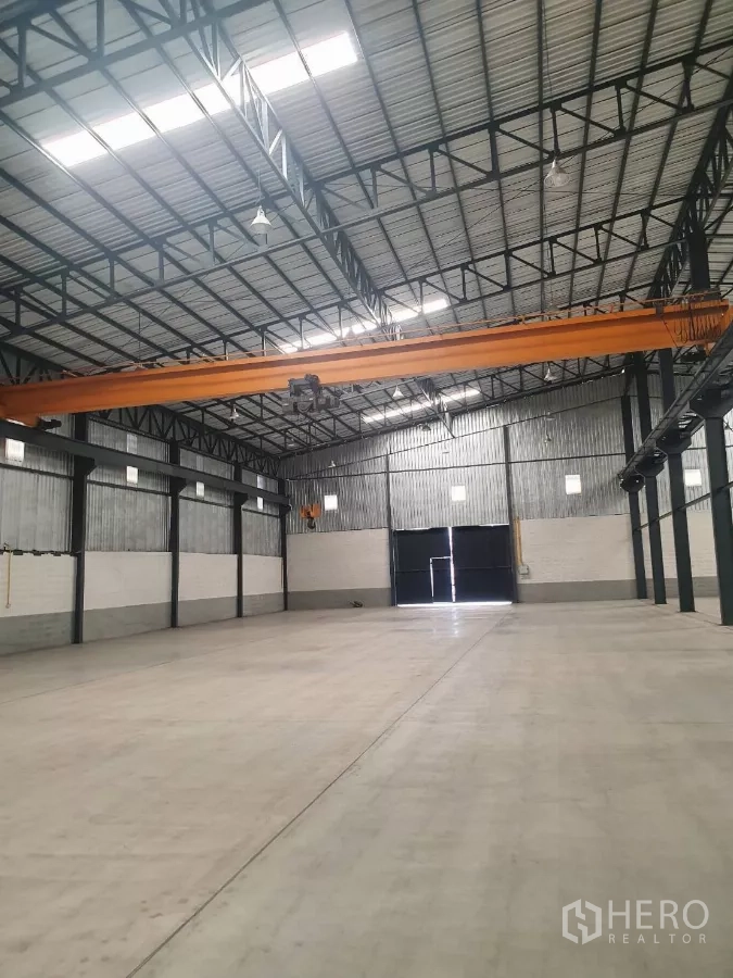 Factory for rent in Mueang Samut Prakan, Samut Prakan - High-clearance warehouse interior with overhead crane and roller door.