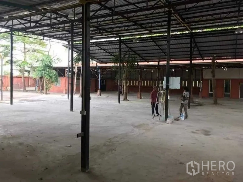 Warehouse for rent or sale in Khlong Sam Wa, Bangkok - Large open-plan shed with concrete floor and an electrical panel beneath a metal roof.