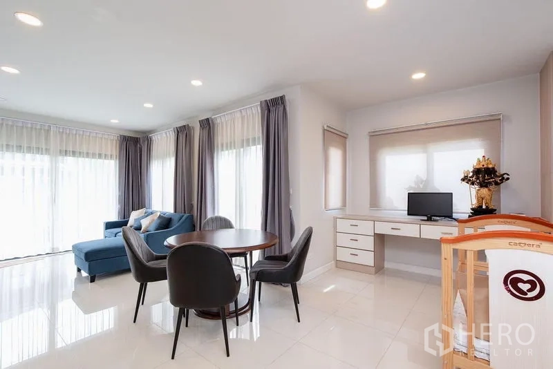 Detached House for rent in Bang Phli, Samut Prakan - Corner of the living and dining area with blue sofa, round table and study desk.