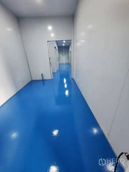 Factory for rent in Lam Luk Ka, Pathum Thani - Clean corridor with glossy blue epoxy flooring and white panel walls leading to workrooms.