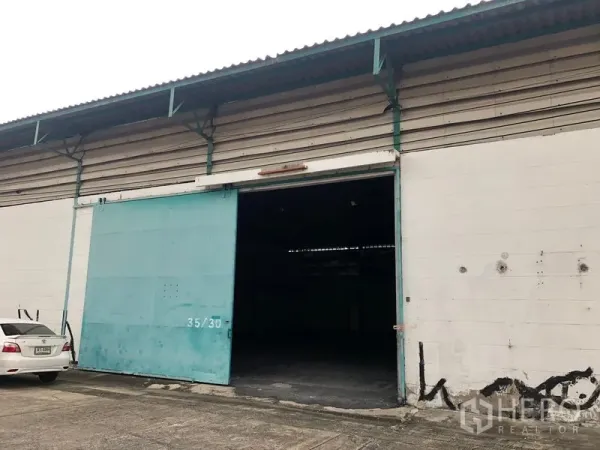 Warehouse for rent in Bang Phli, Samut Prakan - Close-up of a warehouse bay featuring a large teal sliding door and concrete loading apron.