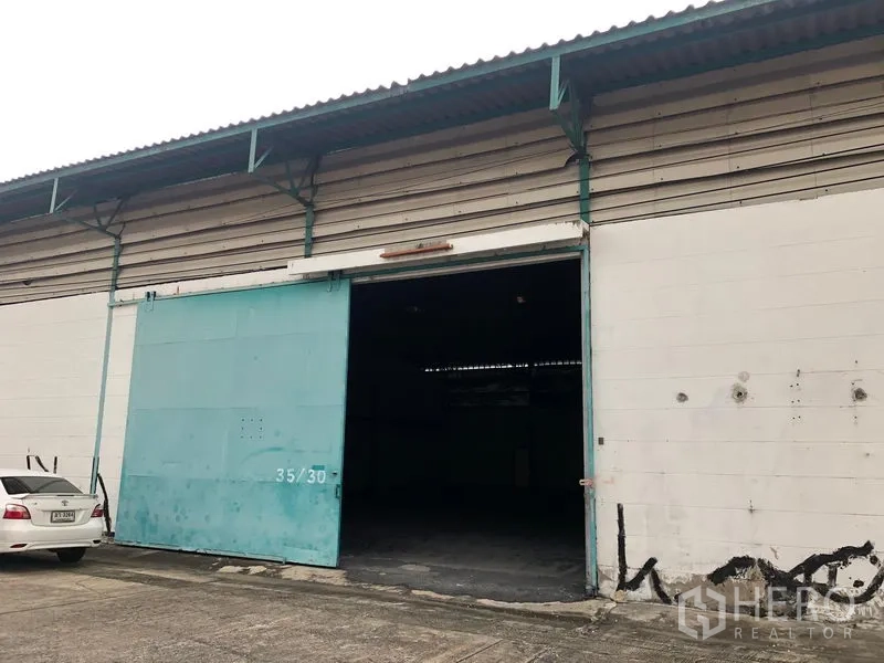 Warehouse for rent in Bang Phli, Samut Prakan - Close-up of a warehouse bay featuring a large teal sliding door and concrete loading apron.
