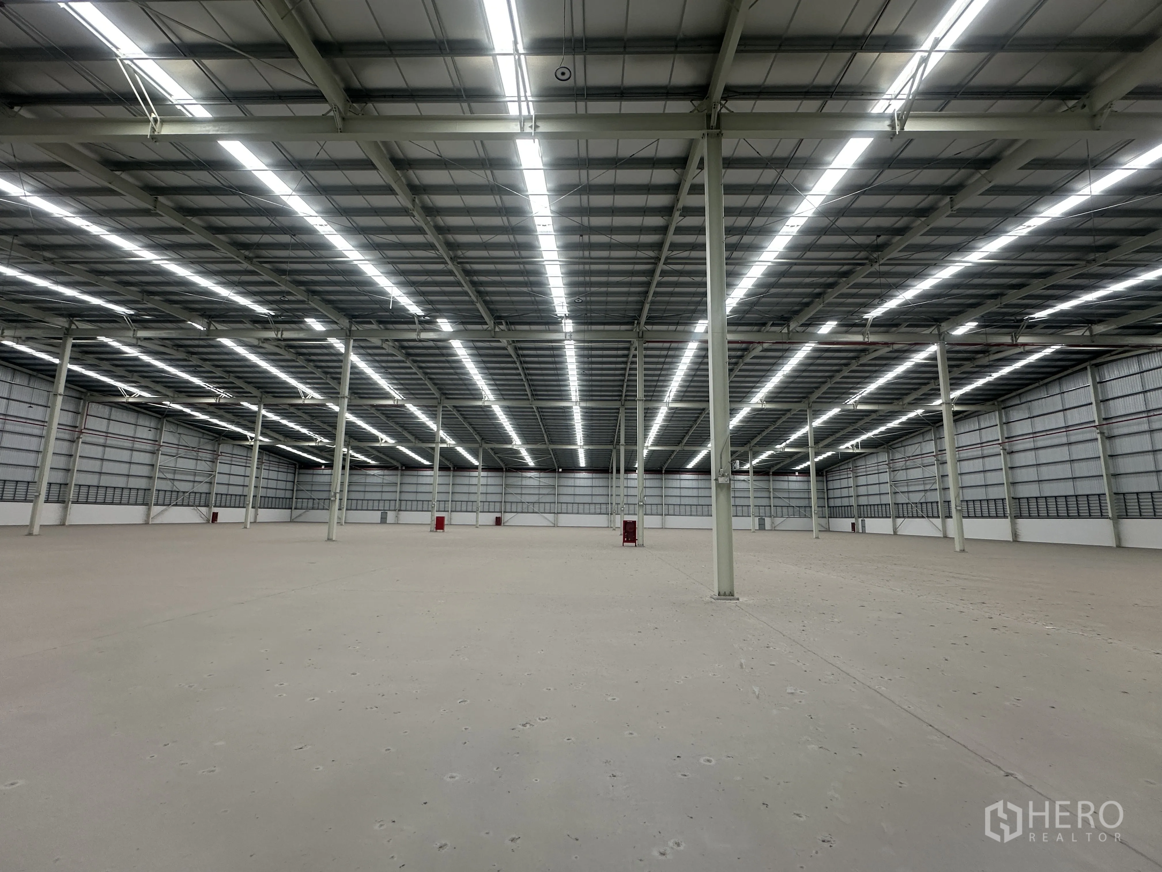Warehouse for rent in Mueang Chon Buri, Chon Buri - Clear-span warehouse interior with bright strip lighting and steel columns.
