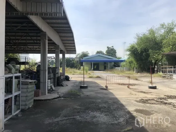 货栈 出租或出售在Lam Luk Ka, Pathum Thani - 开放式棚库配金属货架，通往蓝顶建筑的大型场地。