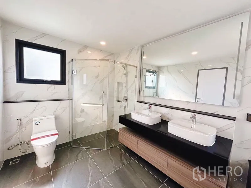 Detached House for rent in Bang Phli, Samut Prakan - Luxury bathroom with double sink vanity, glass shower enclosure and marble walls.