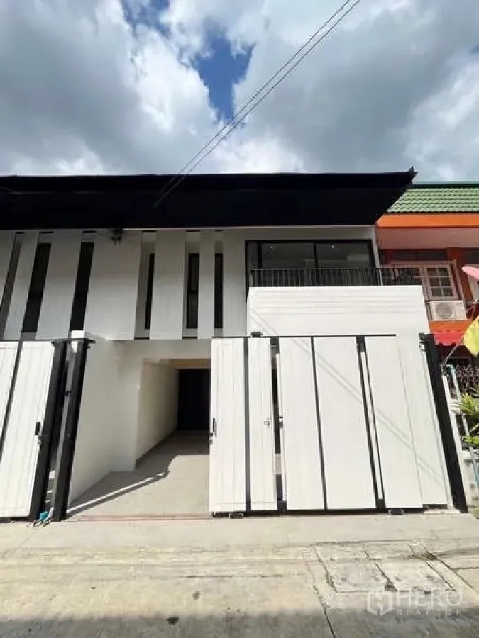 Townhouse for sale in Khlong Toei, Bangkok - Front facade of the renovated townhouse with driveway and sliding gate.