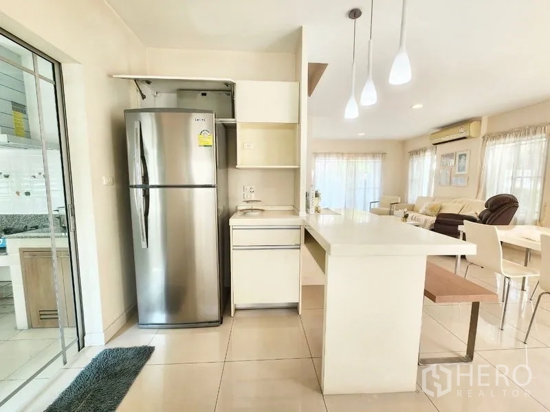 Detached House for rent in Prawet, Bangkok - Open-plan living with a breakfast bar, pendant lights and a stainless refrigerator beside the lounge.