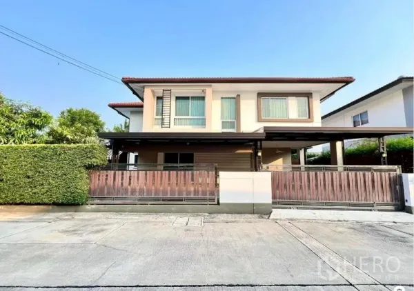 Detached House for sale in Bang Kruai, Nonthaburi - Two-storey detached house with gated carport and privacy hedge on a quiet street.