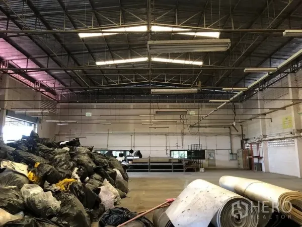 Factory for sale in Lam Luk Ka, Pathum Thani - Steel truss roof with skylights and suspended lights over an open production area.