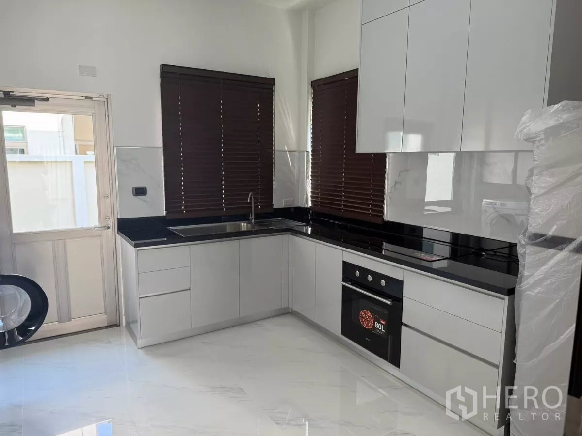 Detached House for rent in Bang Phli, Samut Prakan - White L-shaped kitchen with black countertops, oven and sink