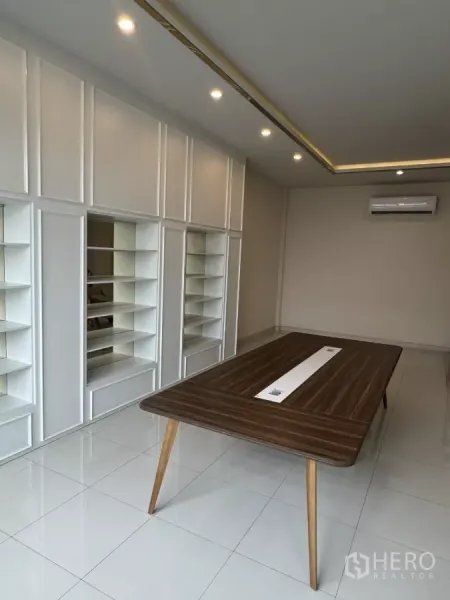 Factory for sale in Lam Luk Ka, Pathum Thani - Air-conditioned meeting room with built-in shelving, a wood table and glossy white tile floor.