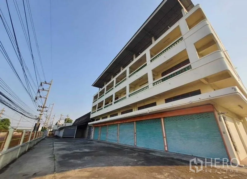 货栈 出租或出售在Mueang Pathum Thani, Pathum Thani - 四层办公/店面楼，带蓝色卷闸门，毗邻仓库园区。