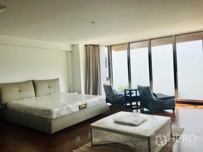 Townhouse for rent or sale in Khlong Toei, Bangkok - Spacious master bedroom with king bed, seating area and floor-to-ceiling glass.