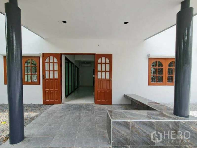 Home Office for rent in Lat Phrao, Bangkok - Covered front porch with tiled floor, built-in bench seating, and double wooden entry doors.