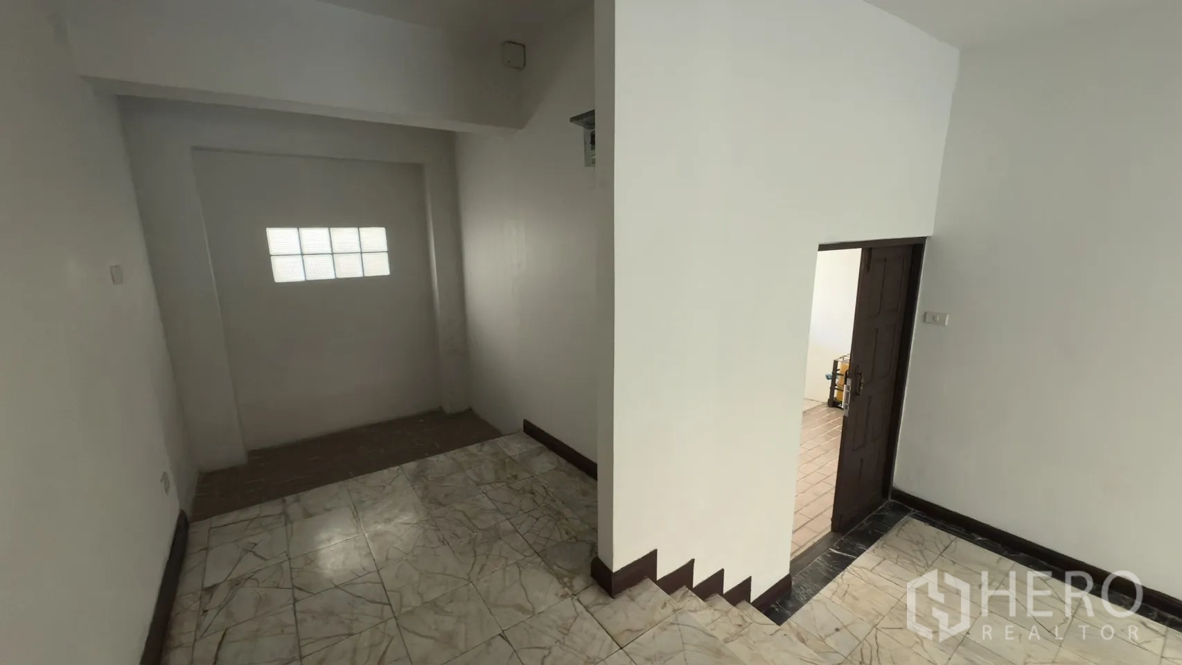 Townhouse for rent in Watthana, Bangkok - Ground-floor hallway corner leading to a service area with tiled floor.