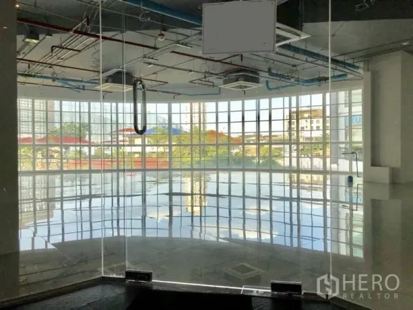Retail Space for rent in Khlong Toei, Bangkok - Curved glass-walled retail unit with polished tile floors and an exposed ceiling, city views through floor-to-ceiling windows.