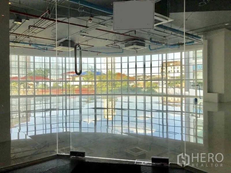 Retail Space for rent in Khlong Toei, Bangkok - Curved glass-walled retail unit with polished tile floors and an exposed ceiling, city views through floor-to-ceiling windows.